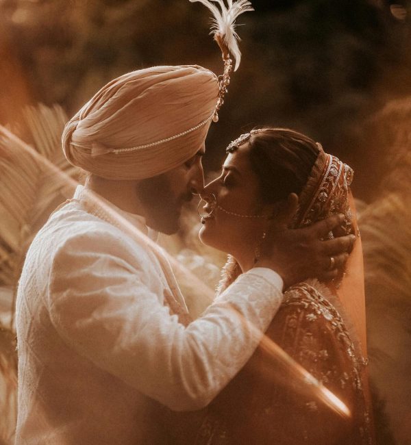 Romantic moment between a traditional wedding couple in elegant attire, captured outdoors.